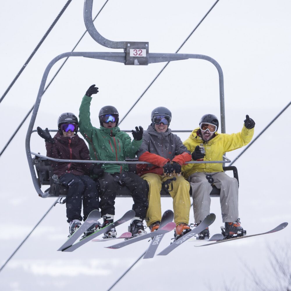 A group of four friends with Quad Tickets riding the chairlift. 