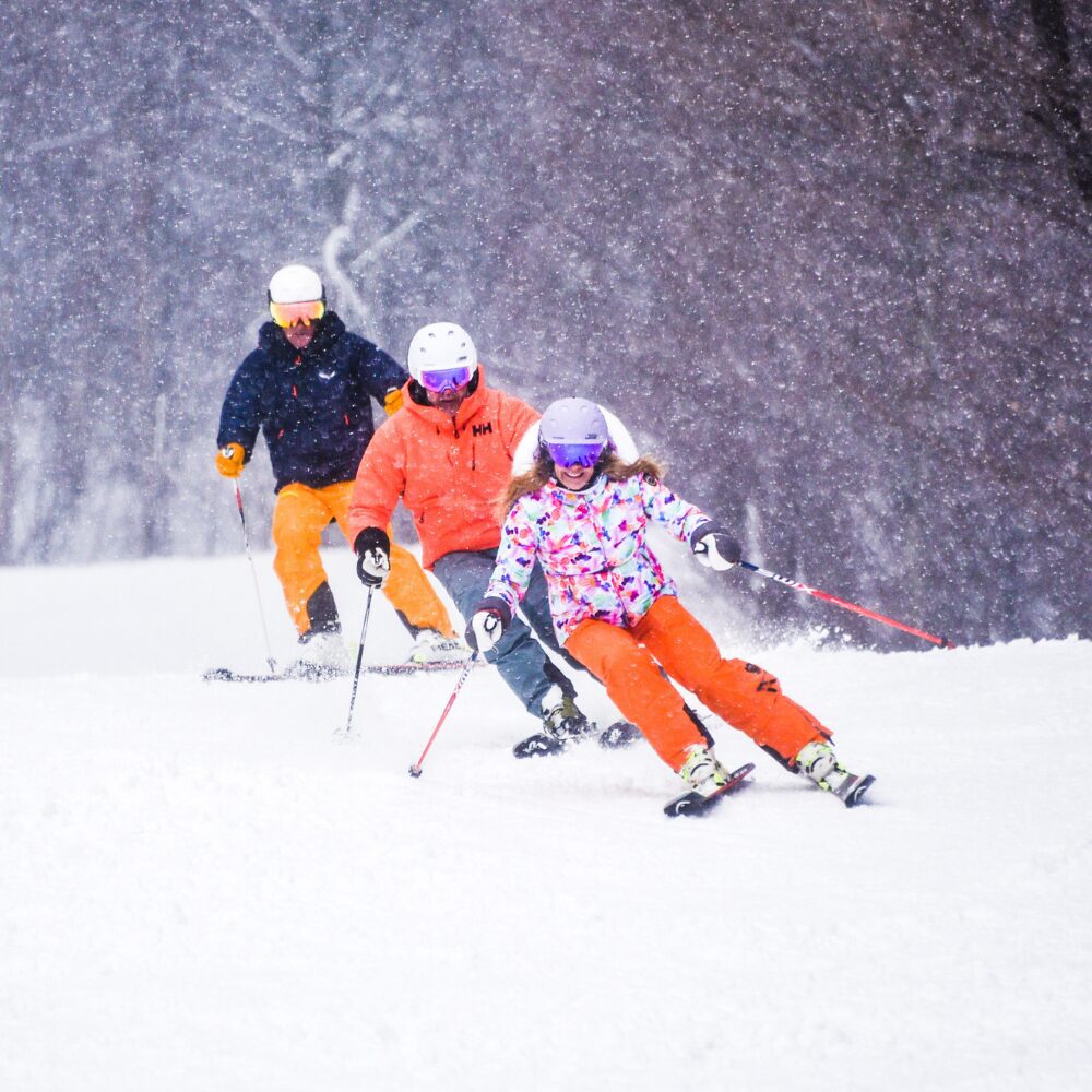 A group of skiers carving down the mountain. 