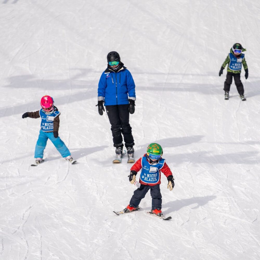 Children in a Schoolhouse Lesson group skiing with an instructor. 