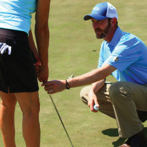 King adjusts a golfer's putting stroke.