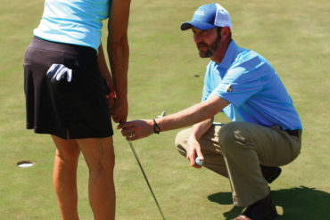 King adjusts a golfer's putting stroke.