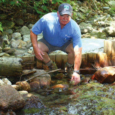 Gene Martin collecting water samples from Clay Brook
